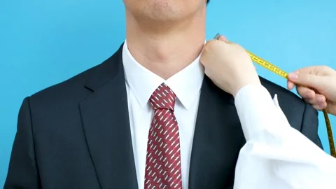 The tailor measures the suit with a measuring tape close-up on a blue background Stock Footage 281037335