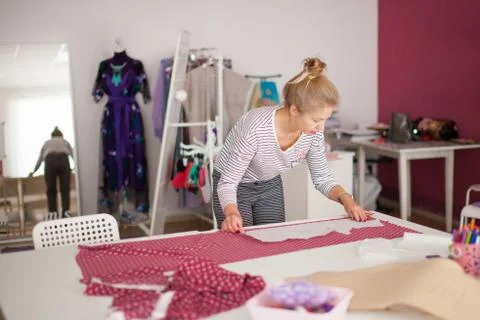 Tailor measuring textile material. young woman seamstress making pattern on f Stock Photos