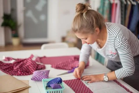 Tailor measuring textile material. young woman seamstress making pattern on f Stock Photos