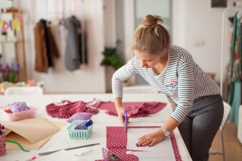 Tailor measuring textile material. young woman seamstress making pattern on f Stock Photos