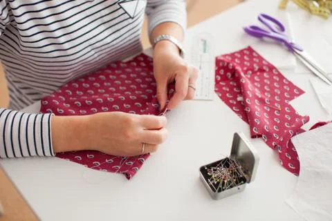 Tailor measuring textile material. young woman seamstress making pattern on f Stock Photos