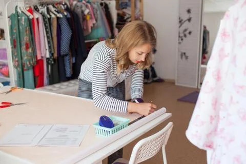 Tailor measuring textile material. young woman seamstress making pattern on f Stock Photos