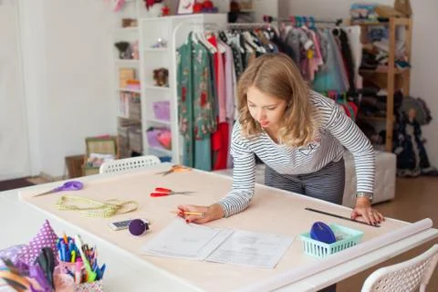 Tailor measuring textile material. young woman seamstress making pattern on f Stock Photos