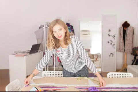 Tailor measuring textile material. young woman seamstress making pattern on f Stock Photos