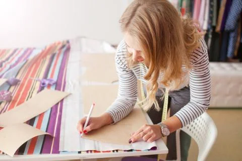 Tailor measuring textile material. young woman seamstress making pattern on f Stock Photos