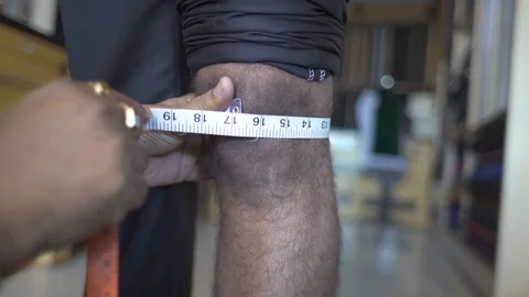 Tailor Measuring Width Of Man Knee With Measuring Tape In A Shop. Close-Up Stock Footage 113273186
