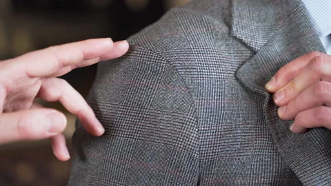 Tailor pointing out tweed jacket shoulder seam at fitting, close up. Stock Footage 208082083