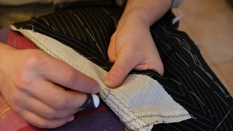 Tailor putting pad stitches in a suit's lapel run parallel to the lapel's roll Stock Footage 127329519
