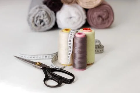 Tailor scissors with thread skewers and cloth on the background on the table Foto stock