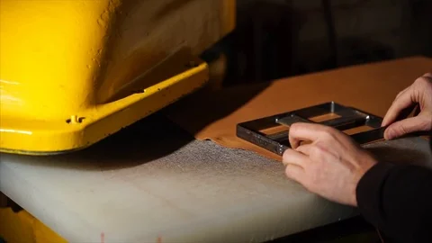 Tailor is setting rectangular metal shape on a leather under press machine Stock Footage 83049548