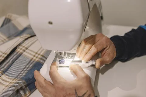 Tailor sewing button with sewing machine on checkered fabric Stock Photos