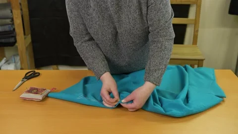 Tailor sewing by hand dress in workshop. Dressmaker working in studio at table. Stock Footage 136098016