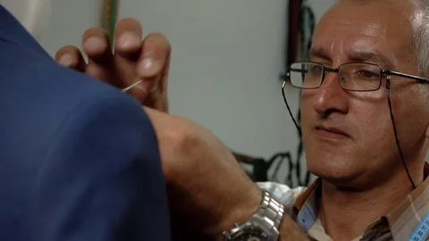 Tailor sews clothes with a needle. Close-up Tailor's face. Slow-motion Stock Footage 73360061