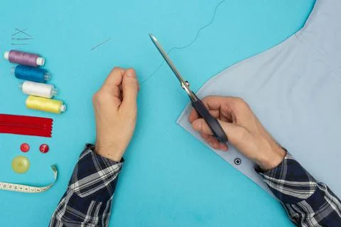 Tailor sews, cuts off the thread. Sewing accessories threads, pins, buttons Stock Photos