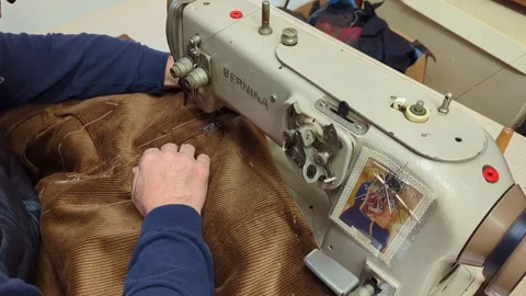 Tailor sews velvet jacket on a sewing machine in a Tuscan artisan tailor's shop Stock Footage 260326543