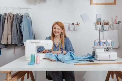 Tailor smiles in her studio while working on a sewing machine. Fashion Designer Stock Photos