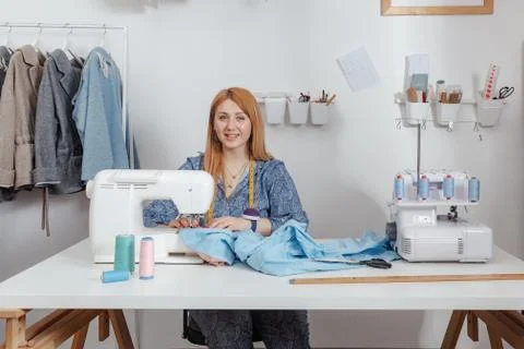 Tailor smiles in her studio while working on a sewing machine. Fashion Designer Stock Photos