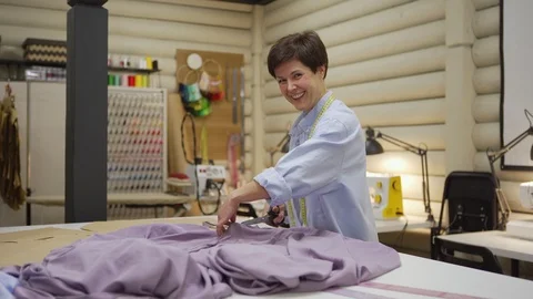 Tailor smiling at camera while cutting fabric Stock Footage 125449072