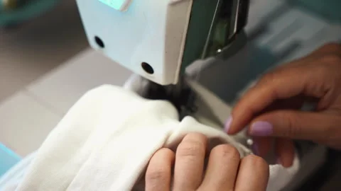 Tailor stitching white fabric with sewing needle and white threads creating Stock Footage 255439080