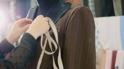 Tailor taking measures with measuring tape on a new brown jacket Stock Footage 107620133
