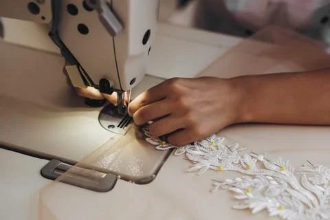 A tailor is using machine for correcting the white ornament. Stock Photos