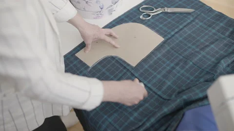 Tailor using sewing pattern, marking fabric, making dress in workshop, design Stock Footage 153998954