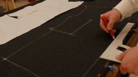 Tailor at work, drawing line on black striped fabric with chalk. Fashion Stock Footage 127218174