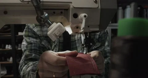 Tailor works on sewing machine in private leather craftshop, making shoes in Stock Footage 200127318