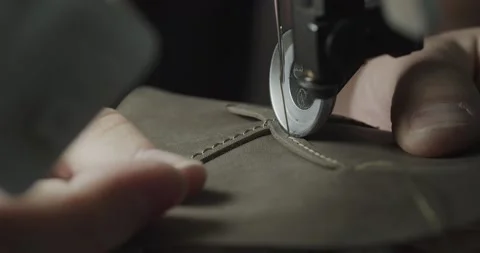 Tailor works on sewing machine in private leather craftshop, making shoes in Stock Footage 200127421