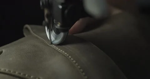 Tailor works on sewing machine in private leather craftshop, making shoes in Stock Footage 200127507