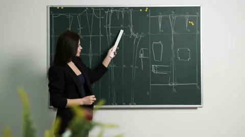 Tailoring teacher explain to her students the Drawing of a pattern on a blackboa Stock Footage 138797250