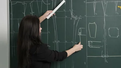 Tailoring teacher explain to her students the drawing of a pattern on a Stock Footage 139749420