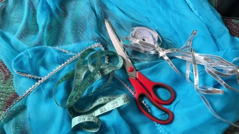 Tailoring tools with red scissors, measuring tape, and silver lace Видео 326123006