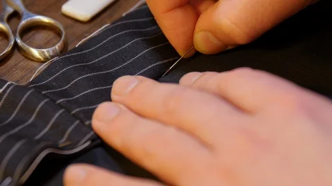 Tailoring tradition : professional motion of young tailor hand sewing with a Stock Footage 127480427
