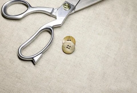 Tailor's scissors lie on a burlap close-up and wooden buttons. Stock Photos