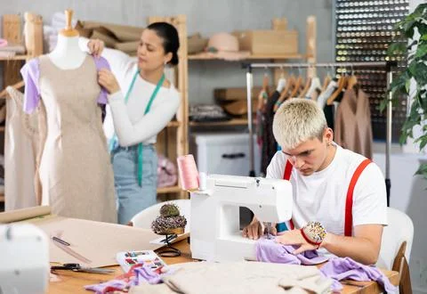 Tailors working in the workshop against the background of shelves with fabrics Foto stock