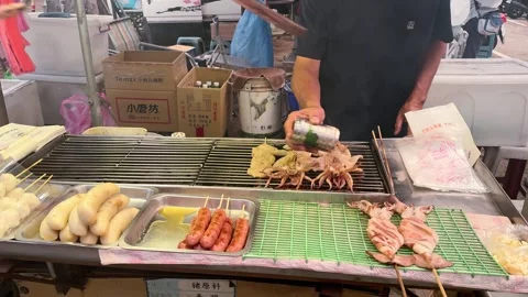 Tainan, Taiwan – 2025, Aug 31: Vendor Grills Squid and Sausages at Stall Stock Footage 341741663