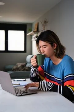 Taiwanese man drinking coffee while working at home with a laptop. 写真素材