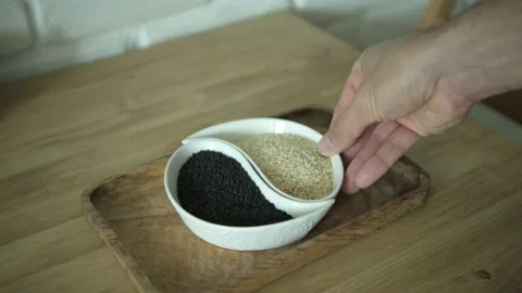 Take and put a plate. White sesame seeds and black sesame seeds on a white plate Stock Footage 161325913