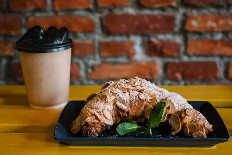 Take away coffee and fresh croissant with mint on wooden background. Cardboar Stock Photos