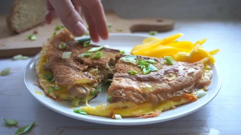 Take a bite of fried omelette with whole grain bread, cheese, green onion Stock Footage 133343384