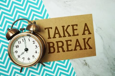Take A Break text written on paper card with alarm clock on marble background Stock Photos