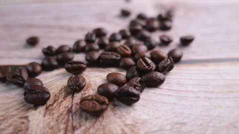 Take a close-up video of coffee beans being poured onto a wooden floor, movin Stock Footage 196901940