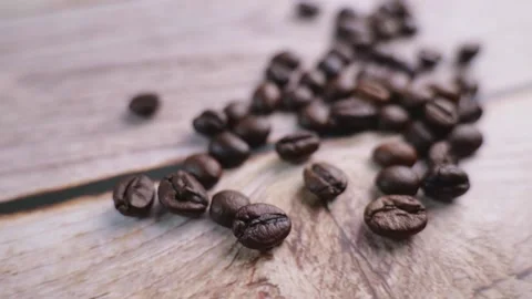 Take a close-up video of coffee beans being poured onto a wooden floor, movin Video stock 196901942
