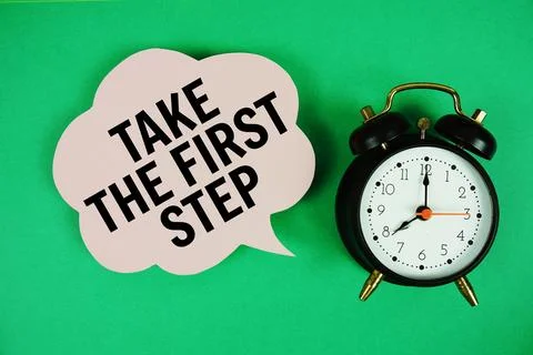 Take The First Step text on speech bubble with alarm clock on green backgroun Stock Photos