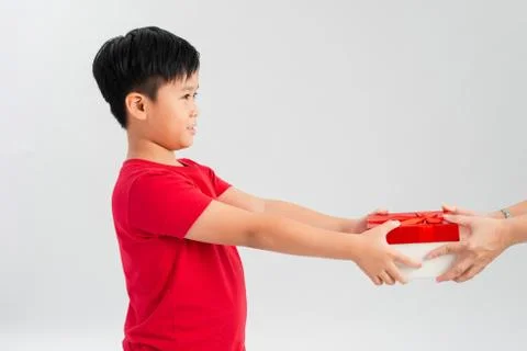 Take it! Side view of joy amazing cute little boy giving gift box to camera w Stock Photos