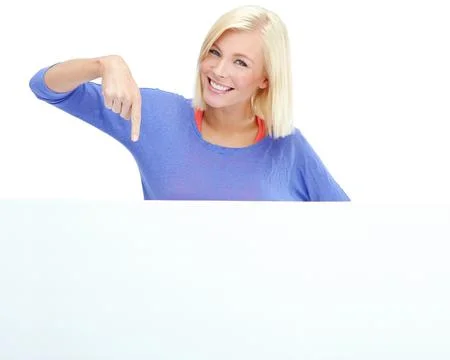 Take a look down here. A pretty young woman pointing at a blank placard while Stock Photos