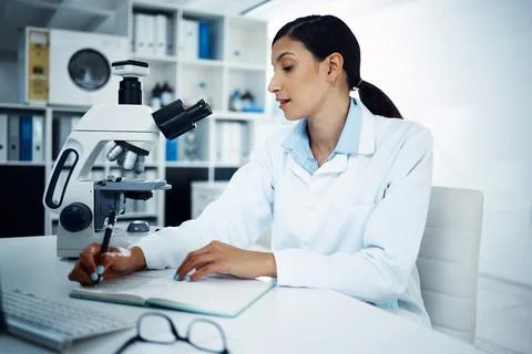 Take note of how expert research is done. a young scientist writing notes while Stock Photos
