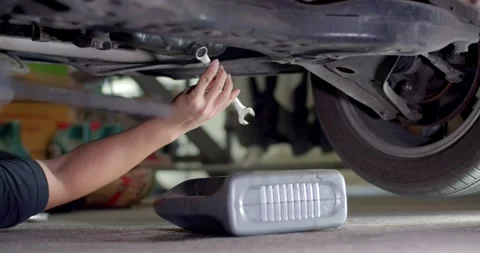 Take the old engine oil out of the engine. Unscrew the nut with a wrench. Stock Footage 267277011
