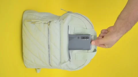 Take out a mobile from a backpack, a turquoise backpack on a yellow background Video stock 251824283
